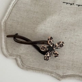 Detailopname van de haarklem met luipaardprint bloem op een getextureerde beige stof - Donkere Thee Bananenclip Luipaardbloem
