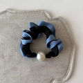 Primer plano de un coletero de satén azul y negro con una elegante perla blanca - Azul Denim Claro Contraste Con Perla