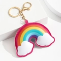 Détail d'un porte-clés arc-en-ciel en cuir avec nuages et mousqueton doré sur socle blanc - Style Arc-en-ciel