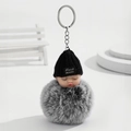 Detailansicht Schlüsselanhänger mit schlafendem Baby, Strickmütze und grauem Pelzball - Schwarz