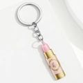 Detailansicht eines lippenstiftförmigen Acrylanhängers mit rosa und goldenen Mustern - Lipstick