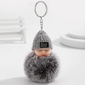 Détails macro d'un porte-clés pompon gris avec un visage de poupée endormie mignon - Gris
