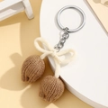 Detail of hand-knitted brown tulip keychain with creamy white bow and silver metal ring - Khaki