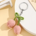 Detailed macro view of hand-knitted pink tulip pendant with a green bow on a key ring - Light Pink