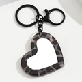 Detailopname van hartvormige sleutelhanger met luipaardprint en zwarte metalen ring - Grijs Hart
