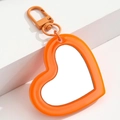 Orange heart-shaped mirror pendant with metallic lobster clasp on minimalist background - Orange