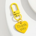 Gros plan d'un porte-clés coeur jaune avec gravure Thank You et fermoir mousqueton - Jaune