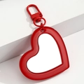 Detalle macro de un llavero de espejo de acrílico rojo en forma de corazón con cierre rojo - Rojo