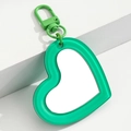 Detalle de un llavero con espejo en forma de corazón verde brillante sobre soporte - Verde