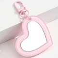 Detail of pink heart-shaped acrylic mirror pendant with metallic lobster clasp on white steps - Pink