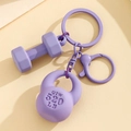 Detailed view of purple fitness keychain featuring textured kettlebell and dumbbell charms - Purple