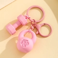 Fitness Schlüsselanhänger in Rosa mit Mini-Hantel und Kettlebell auf beigem Grund - Rosa