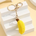 Makroaufnahme eines handgehäkelten Bananenanhängers mit goldenem Karabinerhaken - Banane