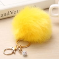 Gros plan sur un porte-clés pompon jaune vif en fausse fourrure avec anneau doré et strass - 8cm / Jaune