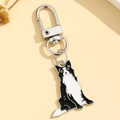 Detail of border collie enamel keychain with silver alloy hook on a warm background - Border Collie