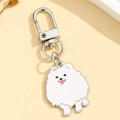 Cute white puppy enamel keychain with silver metal hook on a warm yellow background - Pomeranian