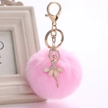 Detail view of pink fluffy faux fur ball keychain with a golden ballerina charm and crystal accents - 8cm Faux Rex Rabbit Fur / Pink