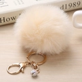 Détail d'un pompon en fausse fourrure beige avec fermoir doré et perle strass arc-en-ciel - 8cm / Blanc Cassé