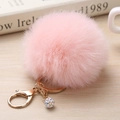 Gros plan d'un porte-clés pompon en fausse fourrure rose avec fermoir doré et strass - 8cm / Rose