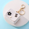 Dettaglio portachiavi a forma di borsa bianca trapuntata con fiori e fiocco nero - Portachiavi borsa stile trapuntato / Bianco