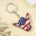 Detail of wooden shaka hand keychain with American flag print on rustic background - American Flag Shaka Gesture