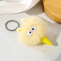 Detail van een gele pluche monster ijsje sleutelhanger met zachte vacht en grote ogen - Beige