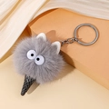 Detail van een pluche monster ijsje sleutelhanger met grote ogen en een metalen ring - Grijs