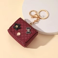 Dettaglio del ciondolo in pelle trapuntata bordeaux con camelia nera e portachiavi oro - Portachiavi borsa stile trapuntato / Borgogna