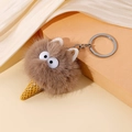 Pluche ijsje monster sleutelhanger met bruine vacht en gele hoorn op zijden decor - Bruin