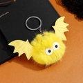 Vue macro du porte-clés chauve-souris en fausse fourrure jaune avec yeux pour Halloween - Jaune