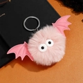 Gros plan d'un porte-clés chauve-souris en peluche rose avec ailes et anneau argenté - Rose