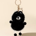 Close-up of black faux fur raccoon keychain with white ears and gold metal hardware - Black