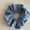 Chouchou bleu esthétique avec bords surjetés blancs sur un fond neutre beige - Bleu Clair Style Denim