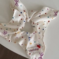Dettaglio dello scrunchie in seta crema con pois colorati e targhetta marchio ciliegia - Stile Ciliegia Pois Bianco Sporco