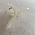 Close-up of a creamy white resin hair claw clip with golden metal spring on fabric - 26#
