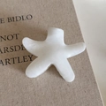 Détail d'une pince à cheveux fleur blanc crème avec texture marbrée sur un livre - Pince Blanche Étoile