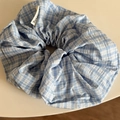 Detailed close-up of blue and white plaid fabric scrunchie with brand woven label - Blue White Plaid Cross Scrunchie