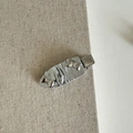 Dettaglio della molletta per capelli a fiocco in pelle argento con accenti metallici lucidi - Stile Fiocco Pieghettato Argento