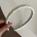 Detail eines blau-beigen karierten gepolsterten Stirnbands mit goldenem Anhänger - Grün Karriert