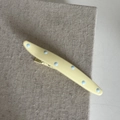 Close-up of cream yellow hair clip with blue polka dots on a textured linen background - Yellow Curved Shape Blue Polka Dot