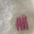 Vue détaillée de quatre barrettes à cheveux rose émaillé dans un sachet zippé - Rouge Rose