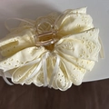 Detail van de crème haarklem met geborduurd kant en een zijden strik accent - Geel