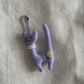 Detail of purple knitted cat plush keychain with pearl necklace and flower embroidery - Purple Cat With Purple Lanyard