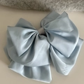 Detalle de elegante pinza de pelo en satén azul claro con un diseño de lazo voluminoso - Azul