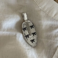 Fermaglio ovale argento con cinque fiocchi neri su uno sfondo di tessuto strutturato - Fiocco d'Argento