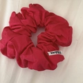 Detalle de un coletero de tela rojo rosa con pliegues elegantes y una etiqueta tejida - Rojo
