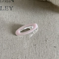 Detailed view of an oval pink enamel hair clip on a natural textured beige fabric - Pink Oval Duckbill Clip