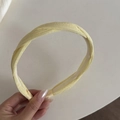Detailansicht eines gelben Stoffstirnbands mit Innenzähnen für festen Halt - Gelber Twist-Stil
