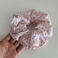 Vista macro dettagliata di un elastico per capelli rosa a fiori tenuto in mano per scala - Rosa