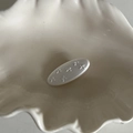 Primer plano de pasador de pelo ovalado blanco con detalles de lazos en relieve - Pinza Ovale Blanca